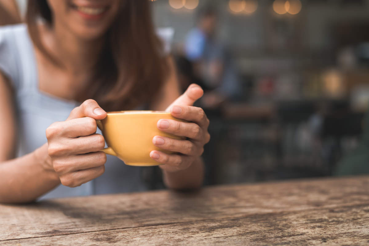 cheerful asian young woman drinking warm coffee tea enjoying it while sitting cafe 1
